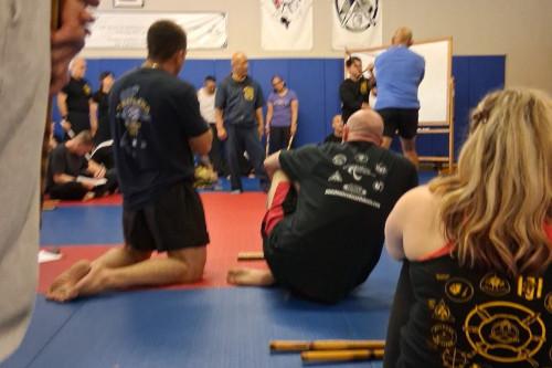 Martial arts training class attendees observing talk and demonstration
